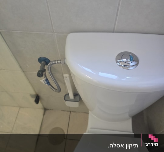 אסלה וניאגרה גלויה עם חיבור צנרת מים ובידה בחדר רחצה